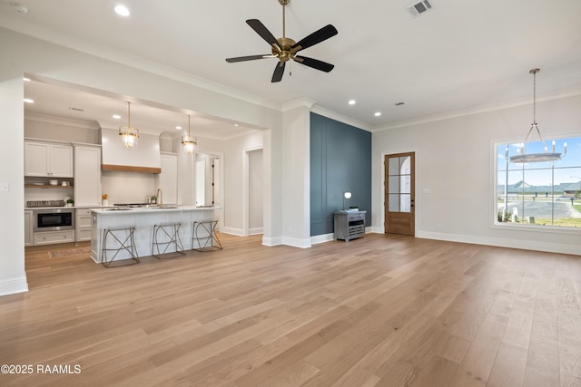 unfurnished living room with crown molding, visible vents, light wood-style floors, a ceiling fan, and baseboards