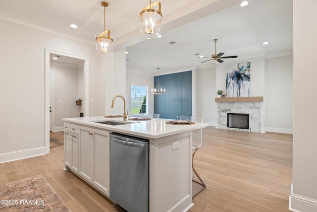 kitchen featuring decorative light fixtures, light countertops, stainless steel dishwasher, white cabinets, and a kitchen island with sink