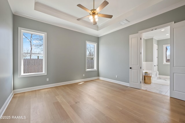 unfurnished bedroom with multiple windows, visible vents, and a raised ceiling