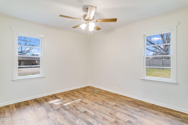 spare room featuring light wood finished floors, baseboards, ornamental molding, and a ceiling fan