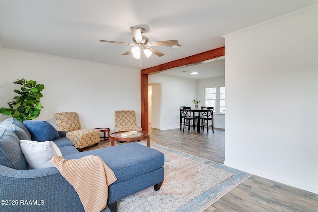 living area featuring ceiling fan, ornamental molding, wood finished floors, and baseboards