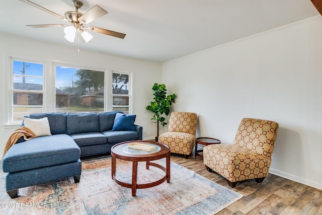 living room with baseboards, wood finished floors, a ceiling fan, and crown molding