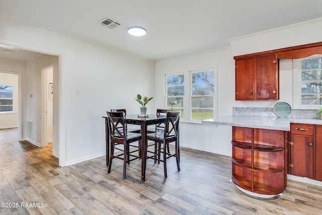 dining room with ornamental molding, baseboards, visible vents, and light wood finished floors