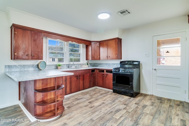 kitchen with light wood-style flooring, a peninsula, light countertops, a sink, and gas stove