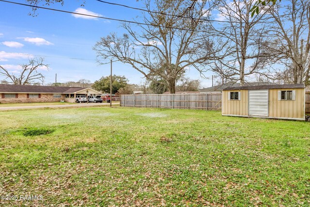 view of yard with a storage shed, fence, and an outbuilding