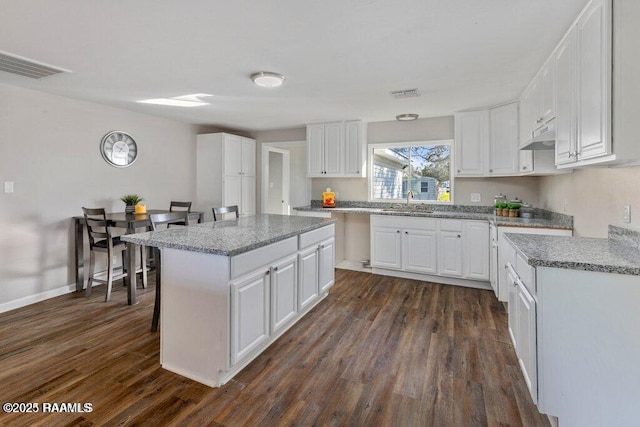 kitchen featuring a kitchen island, dark wood-type flooring, sink, and white cabinets