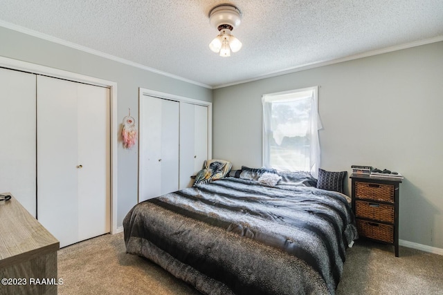 bedroom featuring two closets, a textured ceiling, and carpet flooring