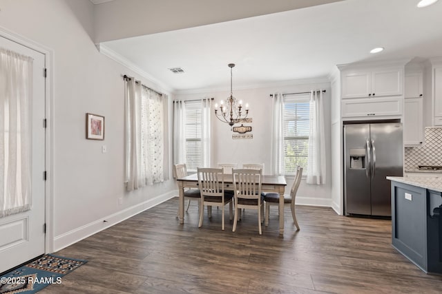 dining area featuring dark wood-type flooring, crown molding, and an inviting chandelier