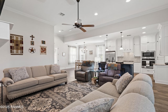 living room featuring crown molding, dark hardwood / wood-style floors, and ceiling fan with notable chandelier