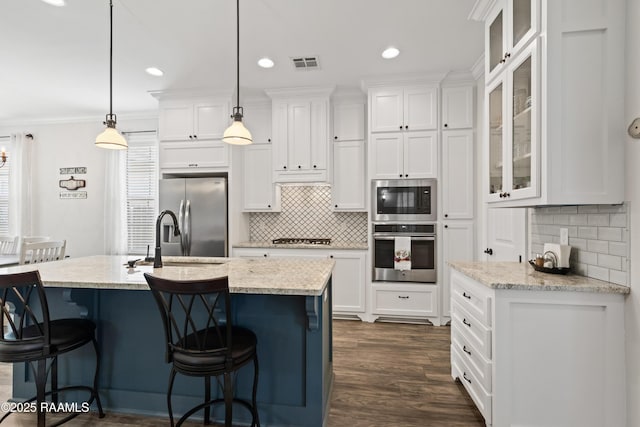 kitchen with stainless steel appliances, hanging light fixtures, white cabinets, and light stone counters