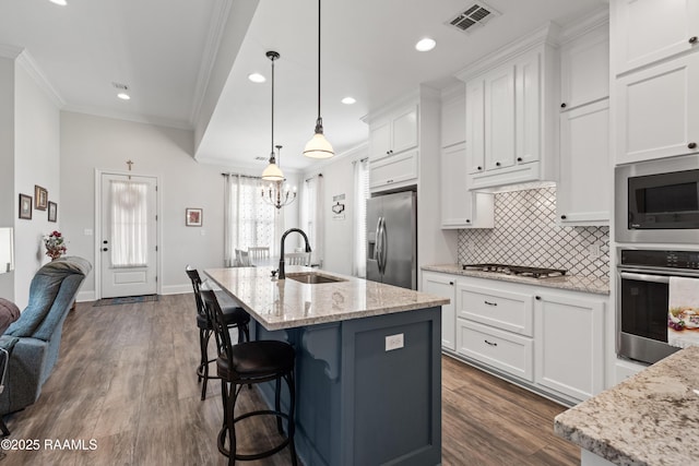 kitchen with appliances with stainless steel finishes, light stone countertops, sink, and white cabinets