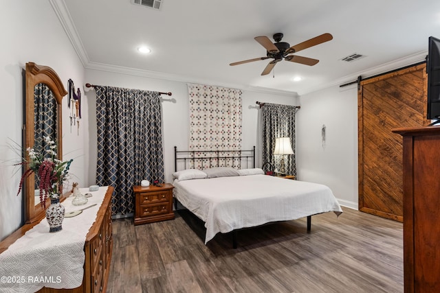 bedroom featuring ceiling fan, ornamental molding, a barn door, and hardwood / wood-style floors