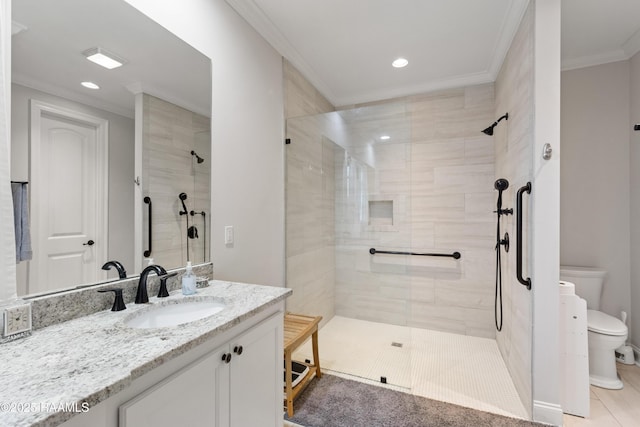 bathroom with a tile shower, vanity, ornamental molding, and toilet