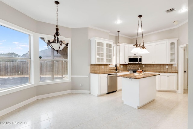 110 Yorkshire Cir, Lafayette, LA 70508 - kitchen with appliances with stainless steel finishes, a chandelier, tasteful backsplash, glass insert cabinets, and ornamental molding