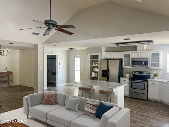 living room with ceiling fan with notable chandelier, dark hardwood / wood-style flooring, and high vaulted ceiling