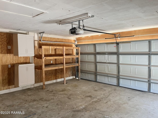 garage featuring a garage door opener and wooden walls