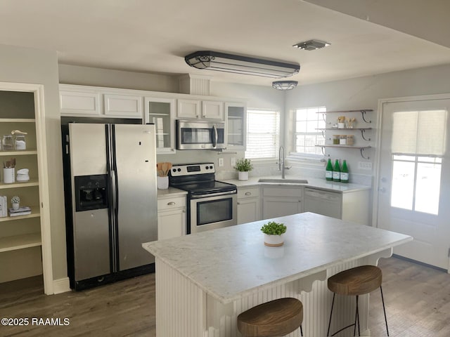 kitchen featuring appliances with stainless steel finishes, white cabinetry, sink, a kitchen breakfast bar, and a center island