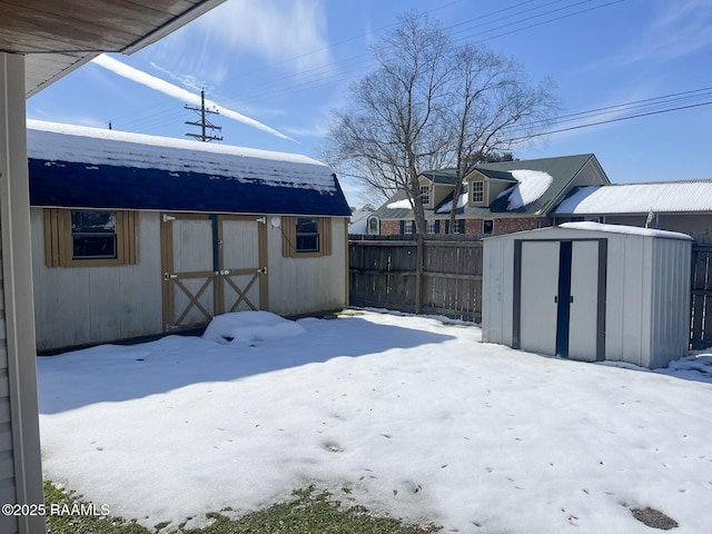 snowy yard featuring a storage shed