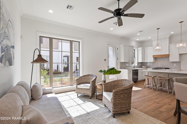 living room featuring crown molding, sink, ceiling fan, and light hardwood / wood-style flooring