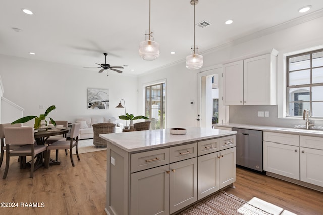 kitchen with sink, white cabinetry, hanging light fixtures, a kitchen island, and stainless steel dishwasher