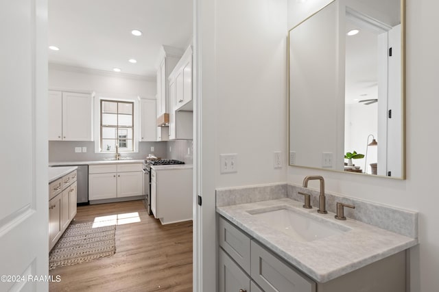 bathroom featuring sink, hardwood / wood-style flooring, ornamental molding, and backsplash