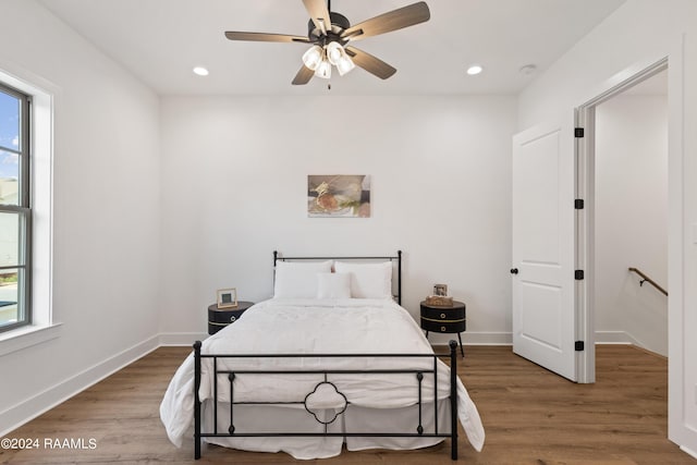 bedroom with hardwood / wood-style flooring, ceiling fan, and multiple windows