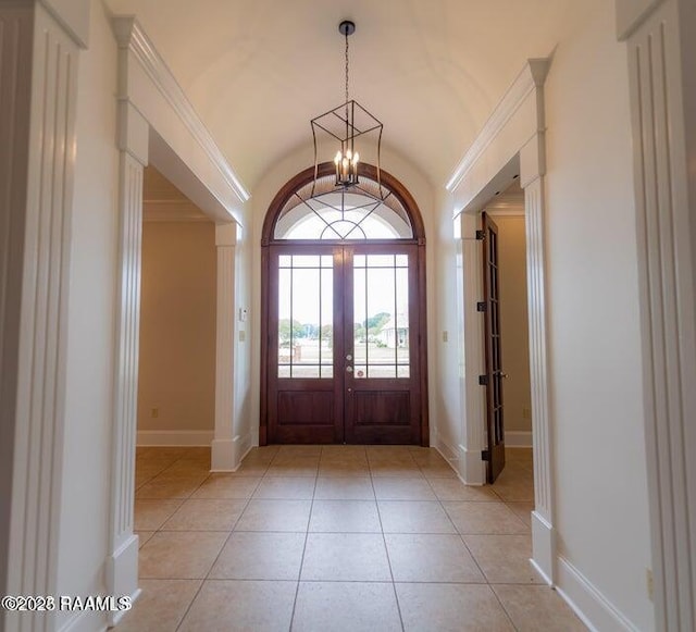 tiled foyer entrance with french doors, lofted ceiling, ornamental molding, and a chandelier