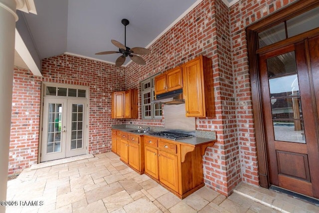 kitchen with vaulted ceiling, brick wall, stainless steel gas cooktop, ceiling fan, and french doors