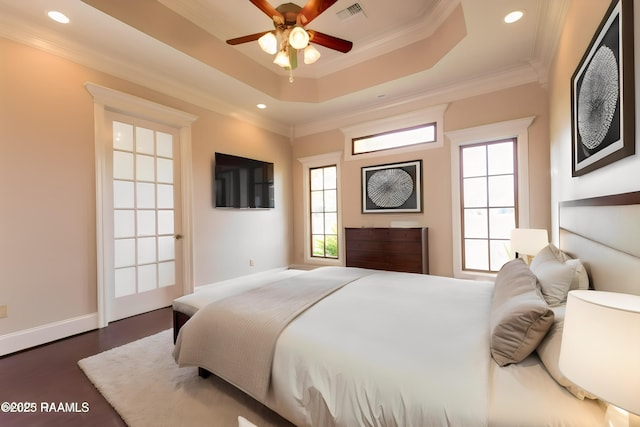 bedroom featuring crown molding, a tray ceiling, and dark wood-type flooring