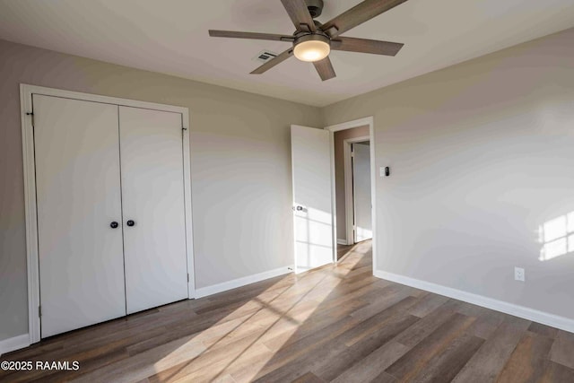 unfurnished bedroom with ceiling fan, dark hardwood / wood-style flooring, and a closet