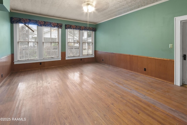 empty room featuring hardwood / wood-style flooring, wooden walls, and ornamental molding