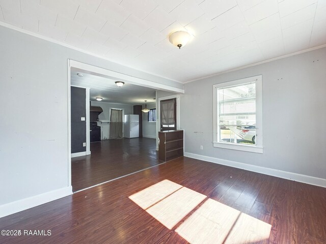 unfurnished living room featuring dark wood-type flooring and ornamental molding