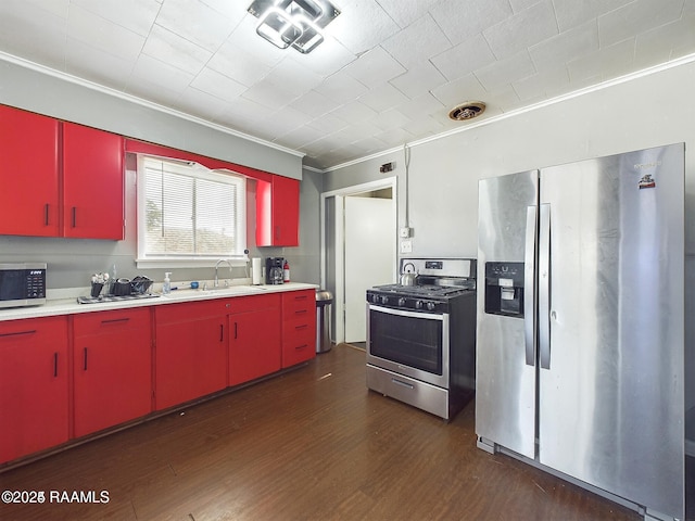 kitchen featuring dark wood-type flooring, ornamental molding, appliances with stainless steel finishes, and sink