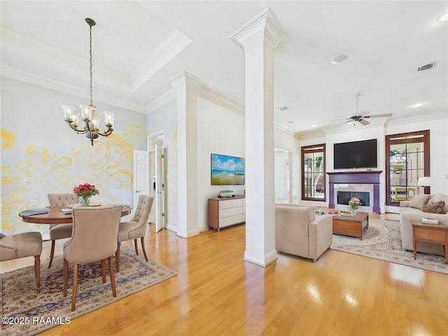 dining room featuring visible vents, a premium fireplace, decorative columns, ornamental molding, and light wood-style floors