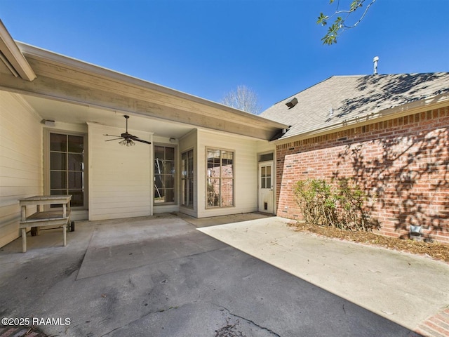 exterior space with brick siding, a patio area, a shingled roof, and a ceiling fan