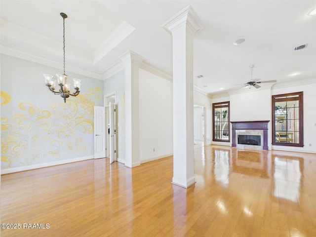 unfurnished living room featuring visible vents, a high end fireplace, light wood-style floors, crown molding, and decorative columns