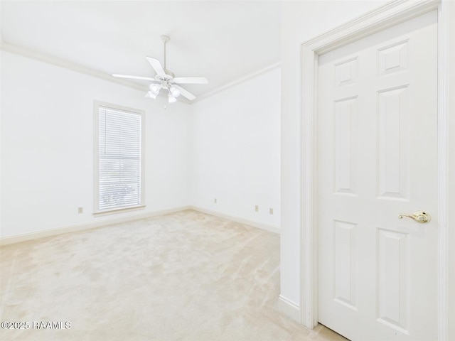 empty room featuring ceiling fan, ornamental molding, baseboards, and light carpet