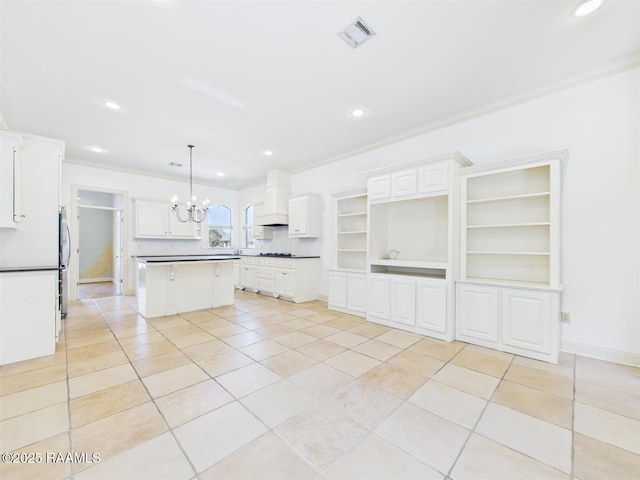 kitchen featuring visible vents, ornamental molding, custom range hood, a kitchen island, and an inviting chandelier