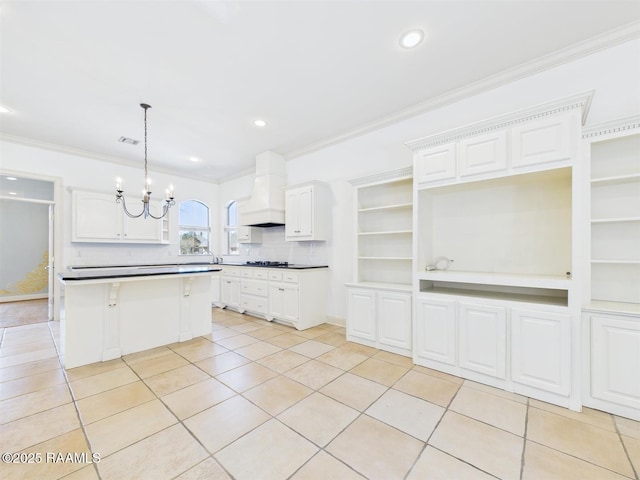 kitchen featuring light tile patterned floors, premium range hood, white cabinets, crown molding, and a chandelier