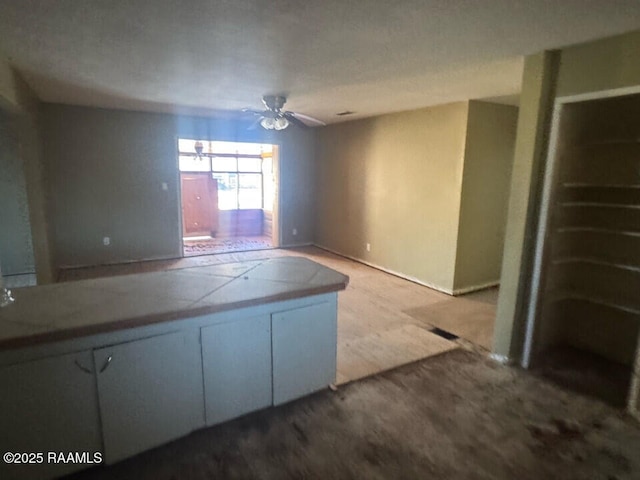 kitchen featuring ceiling fan and white cabinets