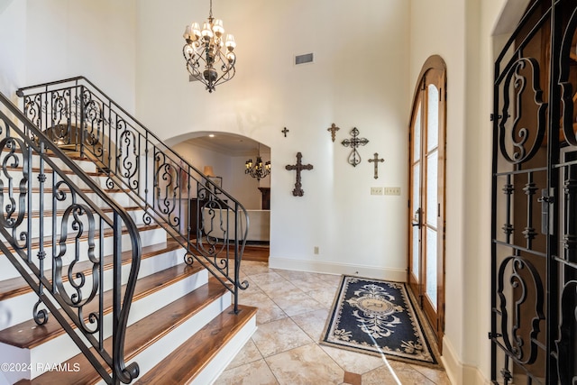 entryway featuring a towering ceiling, a chandelier, and a wealth of natural light