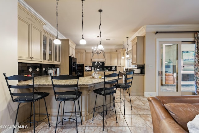 kitchen featuring light stone counters, a kitchen bar, crown molding, and decorative light fixtures