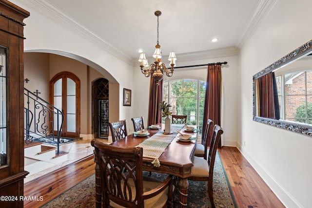 dining room with a notable chandelier, crown molding, and light wood-type flooring