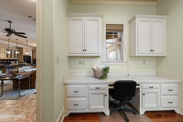 office area featuring ceiling fan, ornamental molding, and built in desk