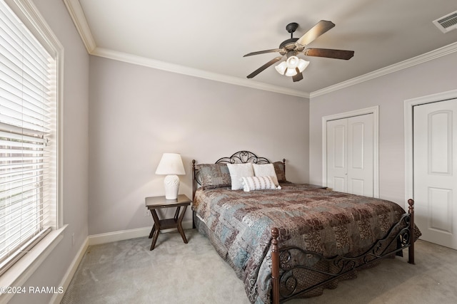 carpeted bedroom featuring ornamental molding, two closets, and ceiling fan