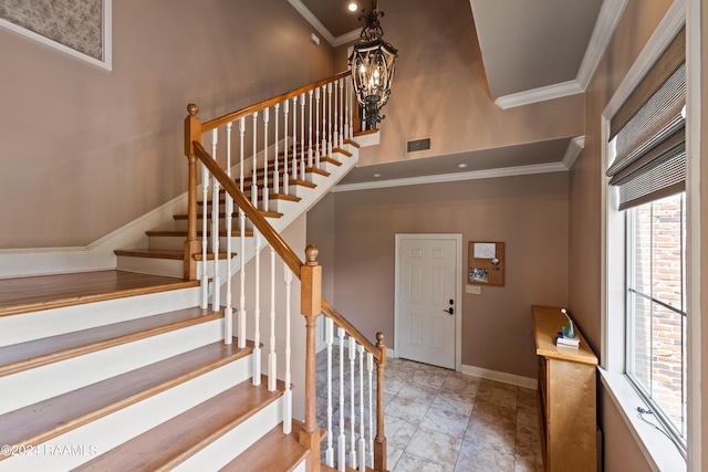 foyer with a notable chandelier, ornamental molding, and a high ceiling