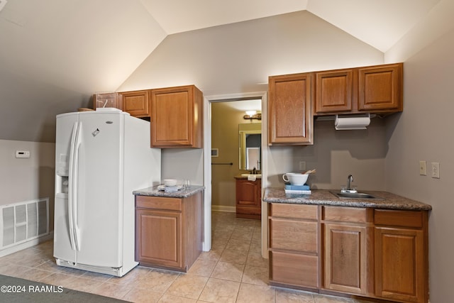 kitchen featuring vaulted ceiling, white fridge with ice dispenser, sink, and light tile patterned floors