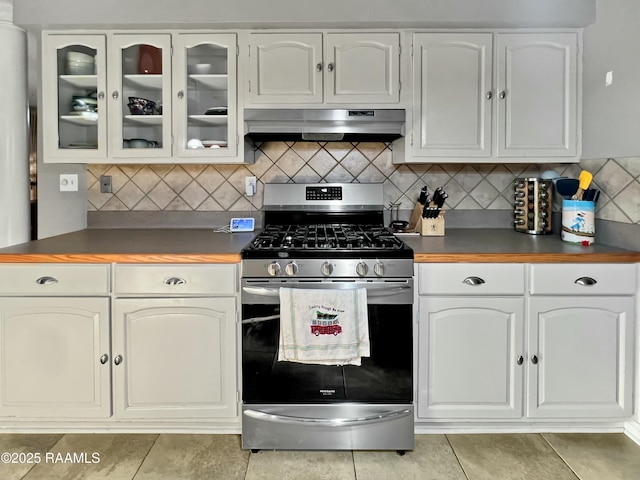 kitchen featuring extractor fan, stainless steel range with gas cooktop, light tile patterned flooring, tasteful backsplash, and white cabinets