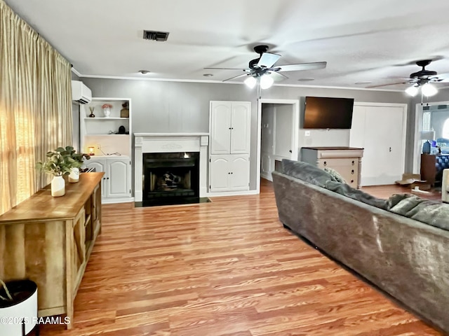 living room featuring a wall mounted air conditioner, crown molding, ceiling fan, and light wood-type flooring