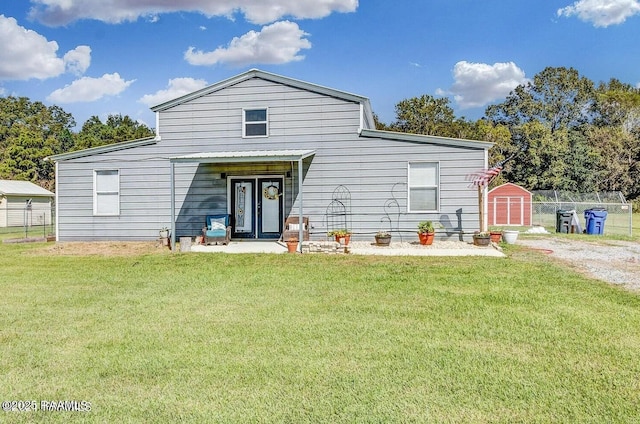 rear view of property featuring a yard and a storage unit